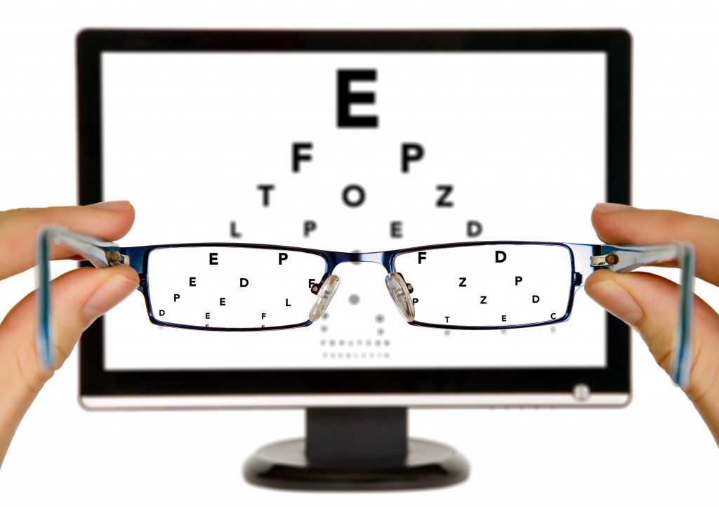 Man is viewing to eye examination chart on display through eyeglasses